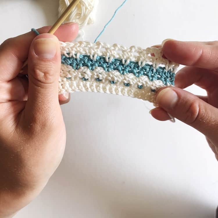 Hands holding white and blue crochet example.