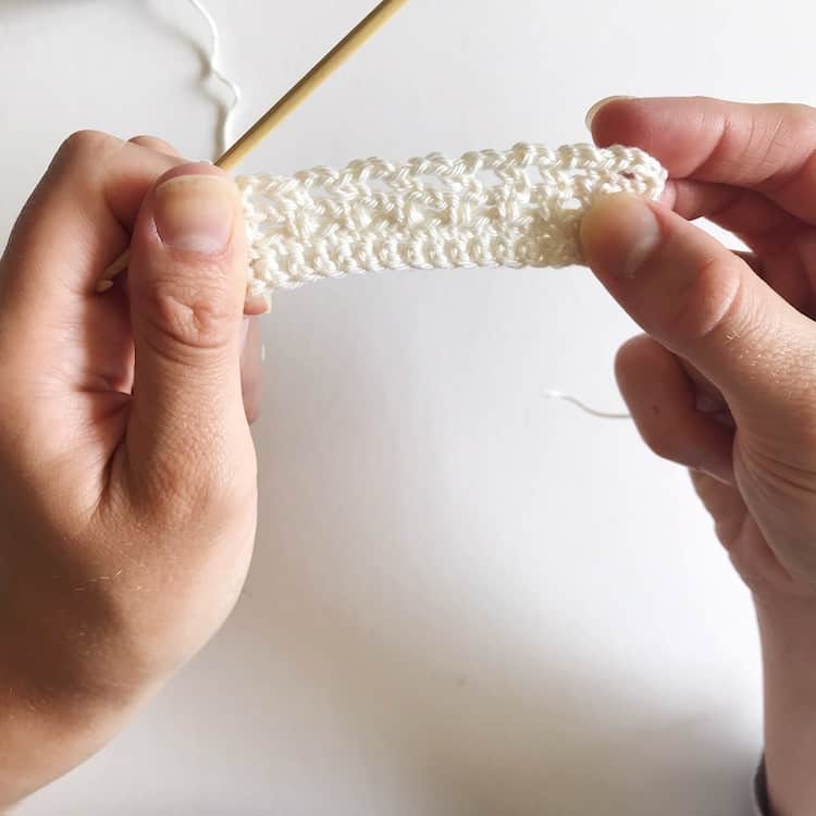 Two hands holding white crochet.