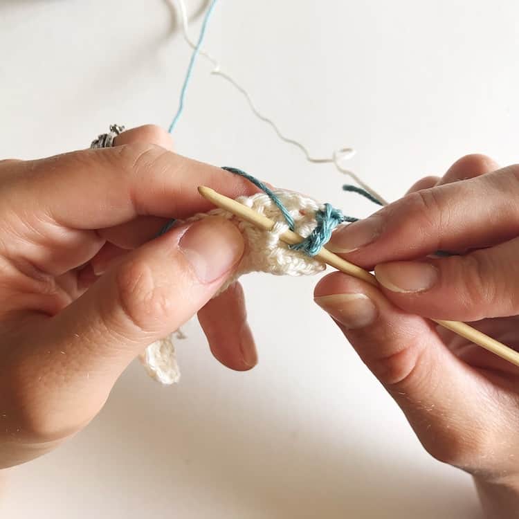 Two hands crocheting.