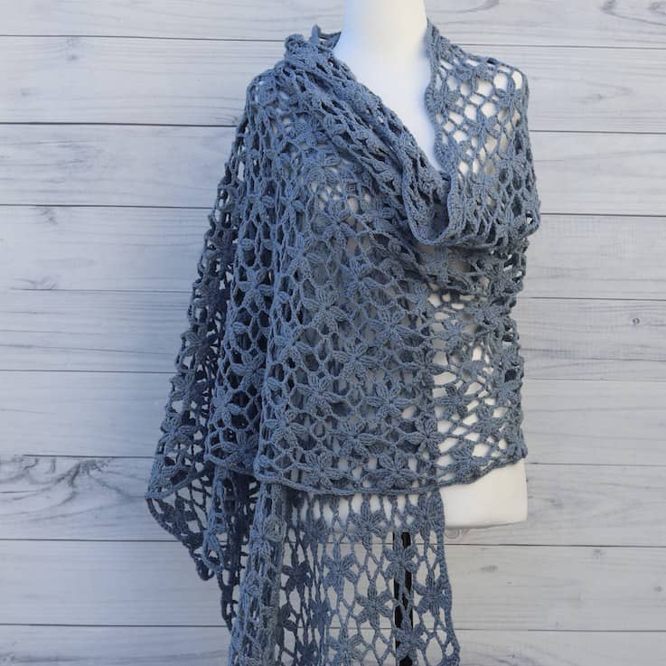 blue flower orchid lace crochet shawl on a mannequin