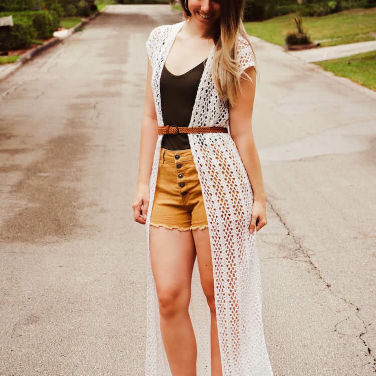 woman wearing shorts and long lace crochet duster cardigan in white