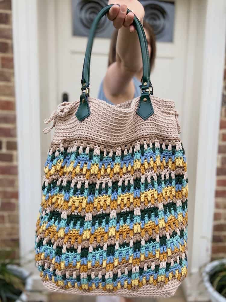 woman holding up mosaic crochet tote bag 