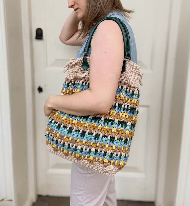 woman with crochet tote bag over shoulder and arm clasped around it