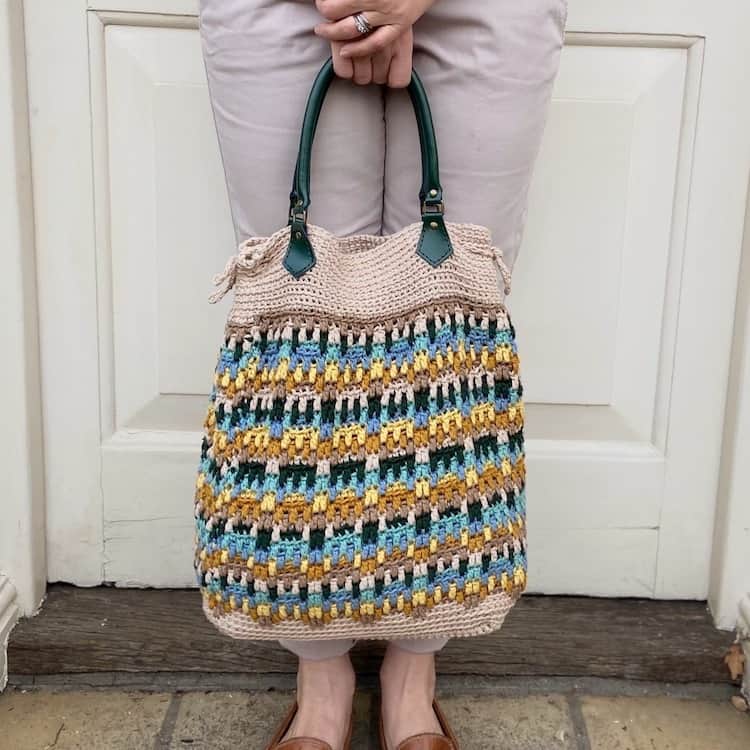 Overlay mosaic crochet tote bag for summer with green handles.