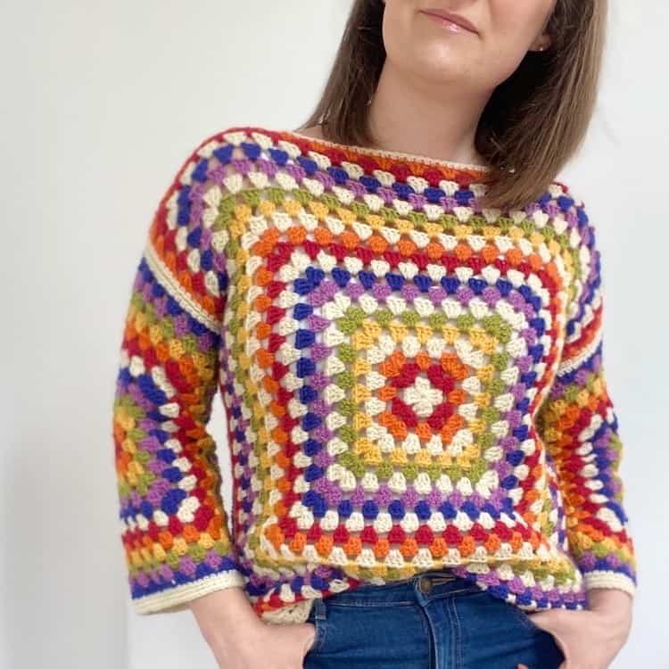 woman wearing rainbow granny square sweater and jeans