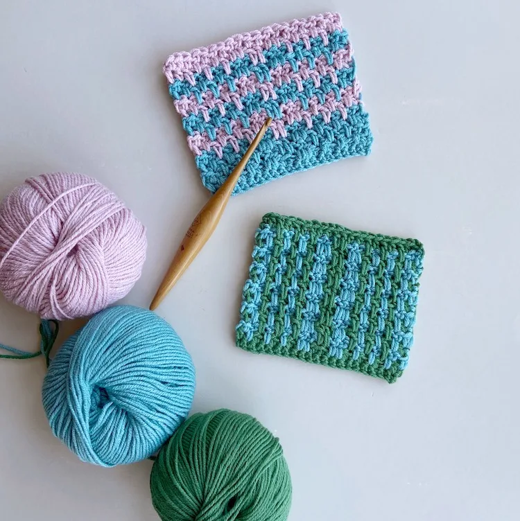 two double crochet moss stitch swatches with wooden Furls crochet hook and three balls of yarn