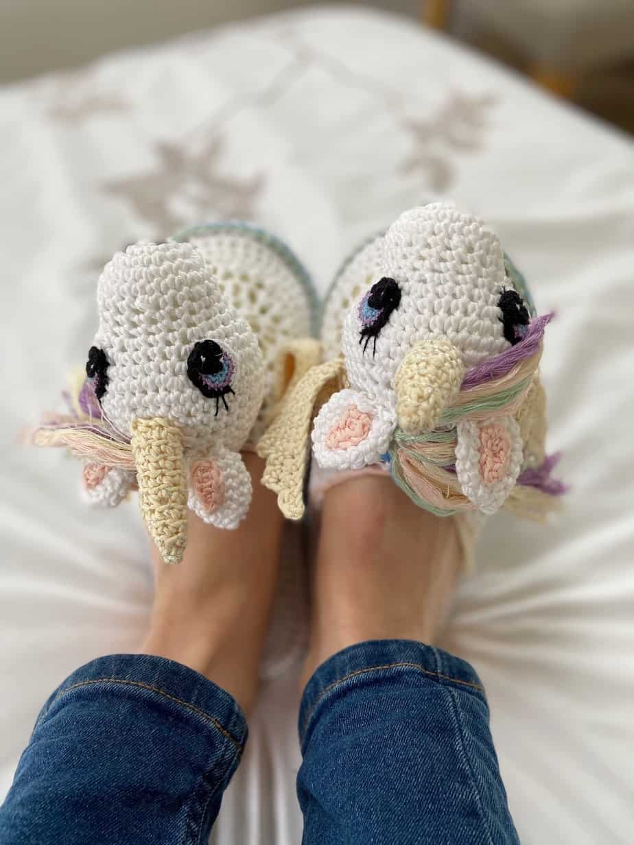 person wearing unicorn crochet slippers with horns, rainbow mane and wings