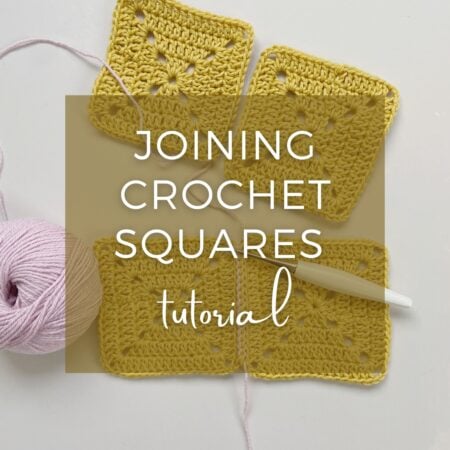 Four yellow crochet squares, a pink ball of yarn, and a white crochet hook on a white surface, overlaid with the text "Joining Crochet Squares tutorial"—perfect for learning the basics of joining crochet squares.