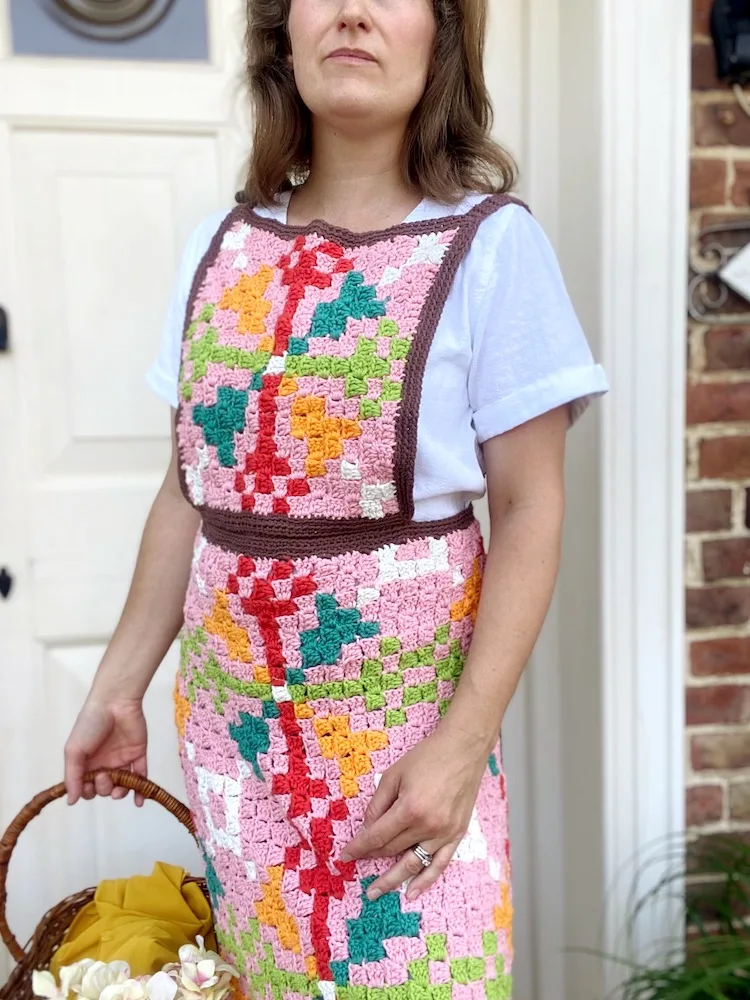 woman wearing c2c crochet apron in vintage colours with a retro geometric design