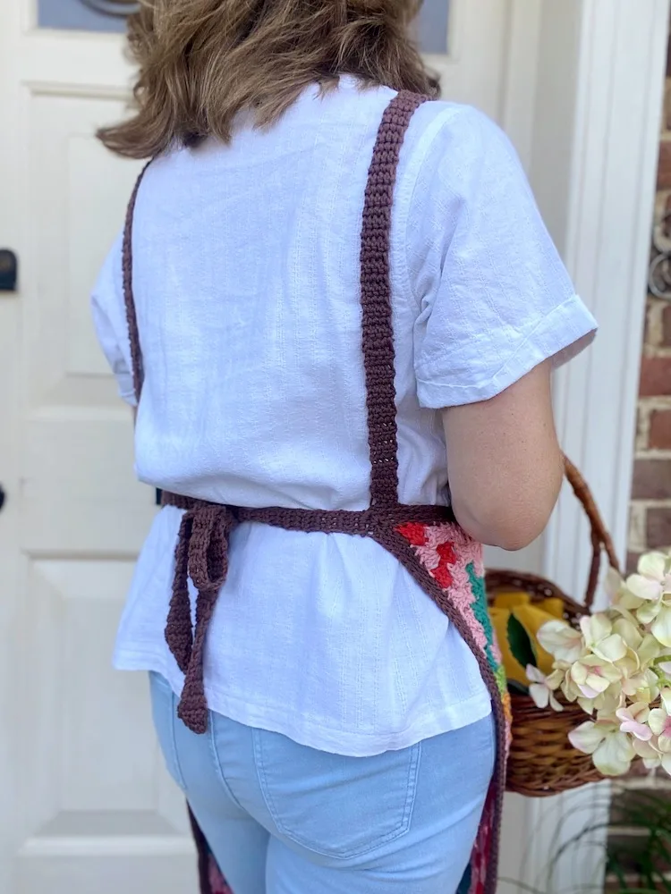 image of back of crochet apron being worn by woman holding basket
