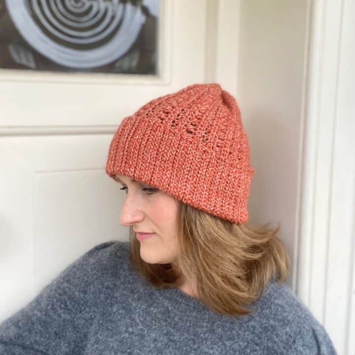 slouchy crochet hat pattern worn by woman against a cream door