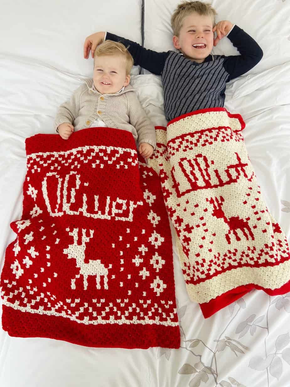 2 children smiling under personalised crochet Christmas blankets