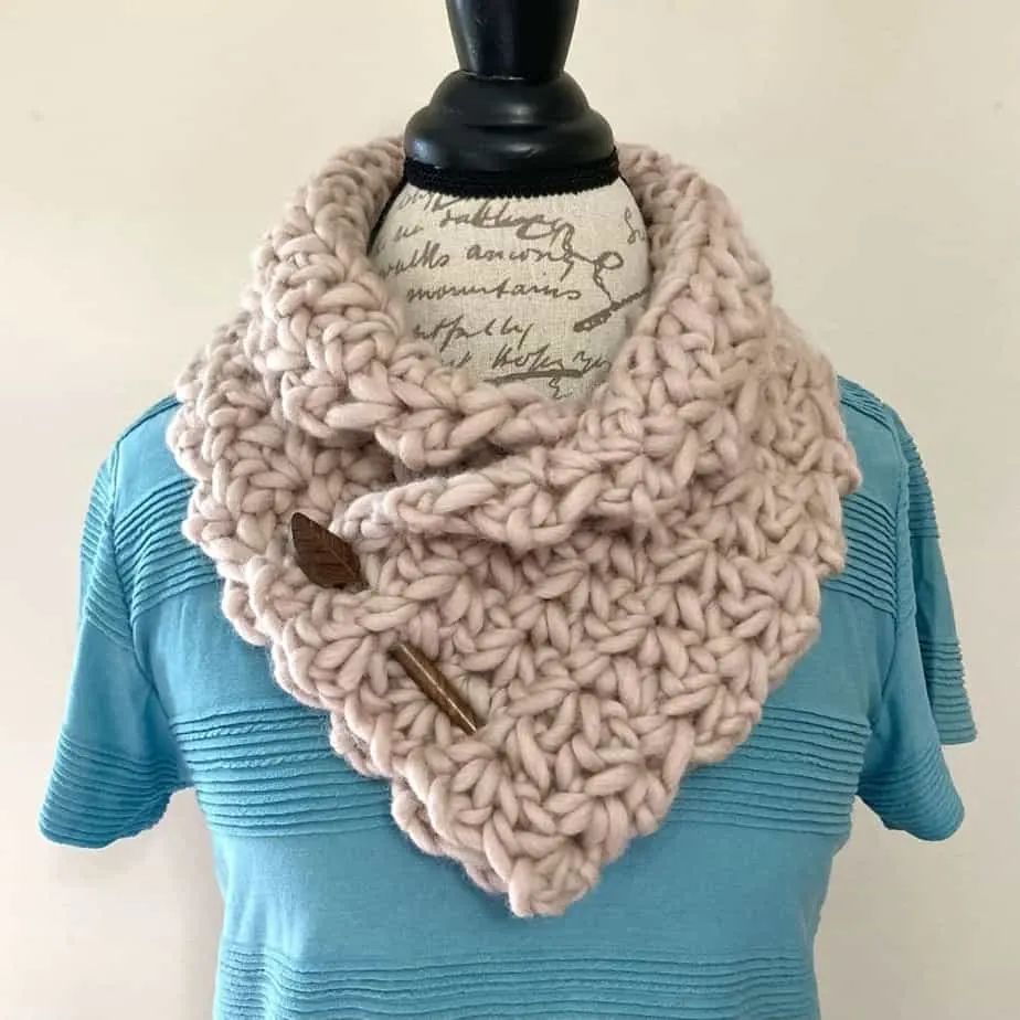 Cream-colored, chunky cowl on a dress form.