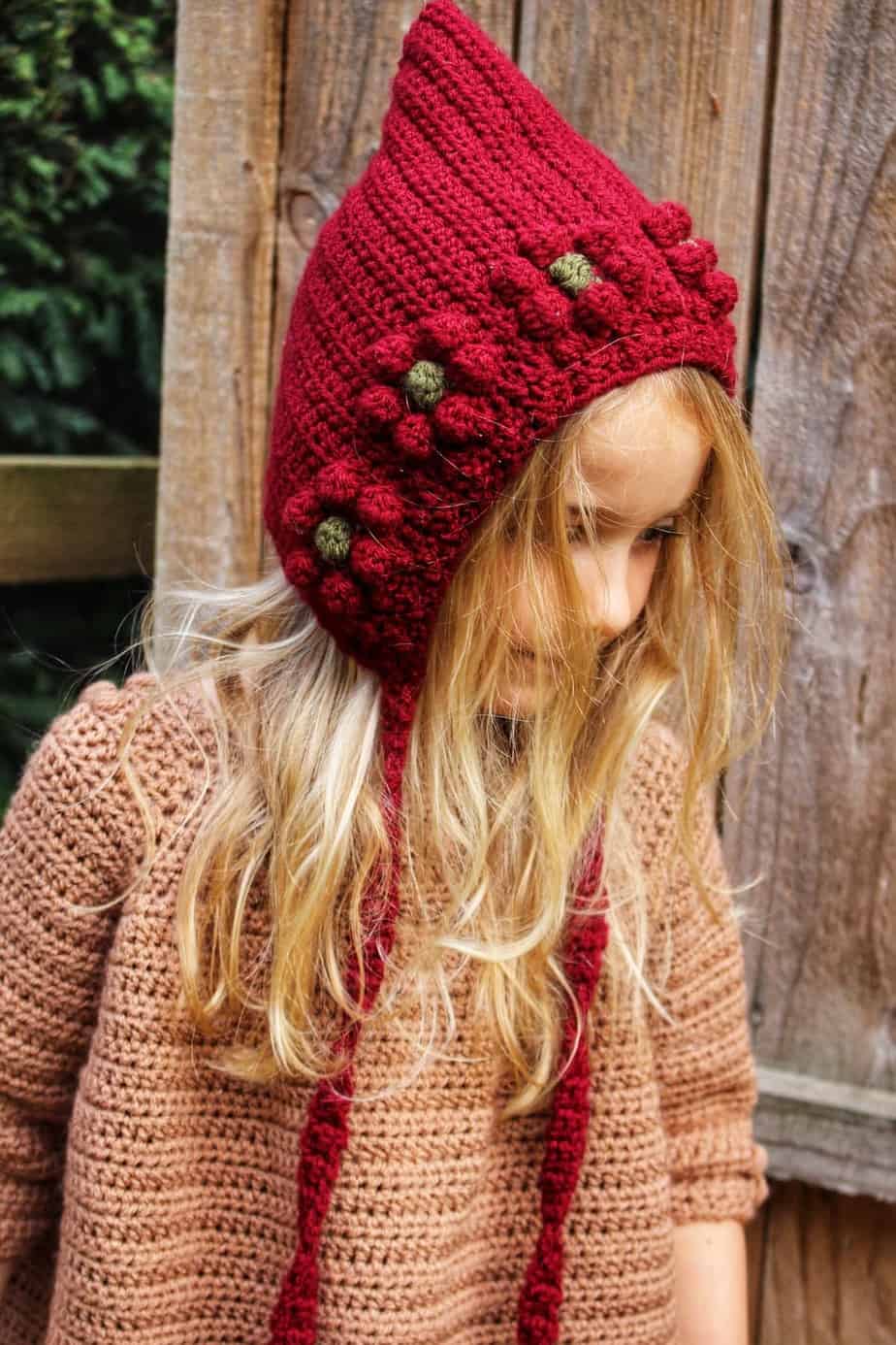 Young girl wearing red crochet flower bonnet.