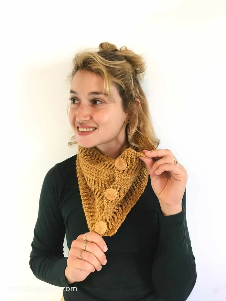 Woman weraing cozy crochet cowl with buttons in mustard yellow.