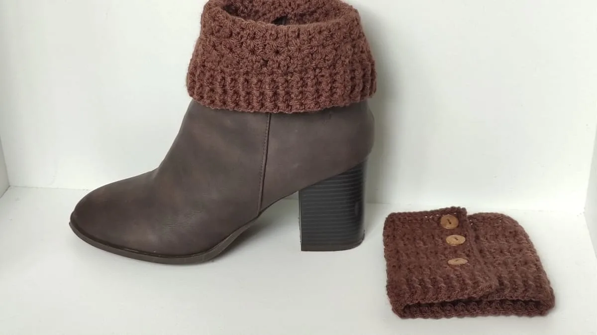 Fashion boot with brown crochet cuff around the top and second cuff on the floor beside it.