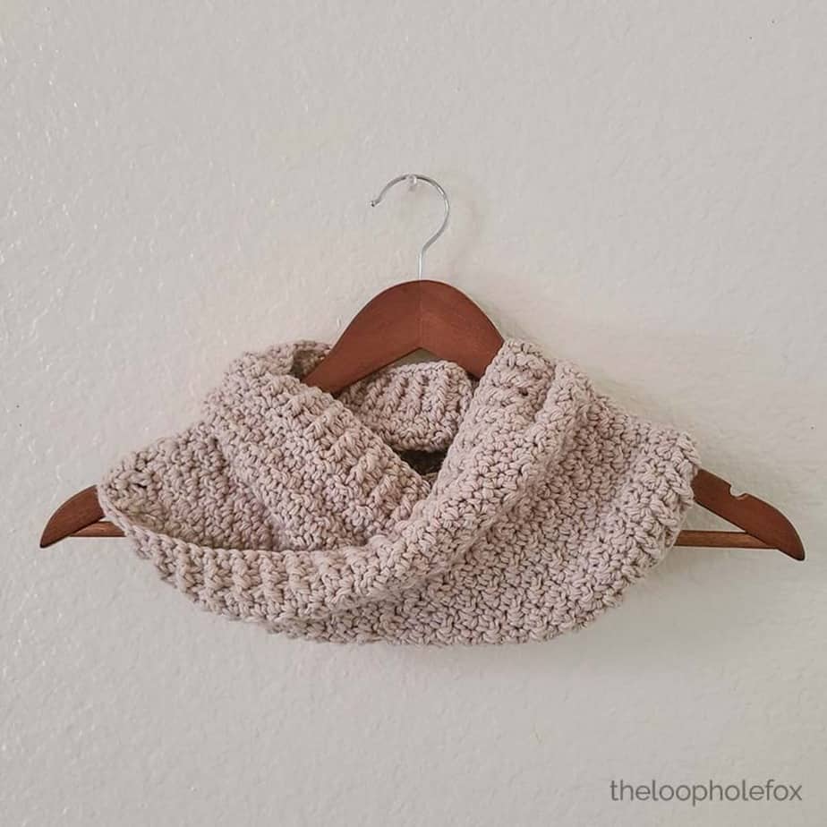 Beige cowl shown draped over a hanger.