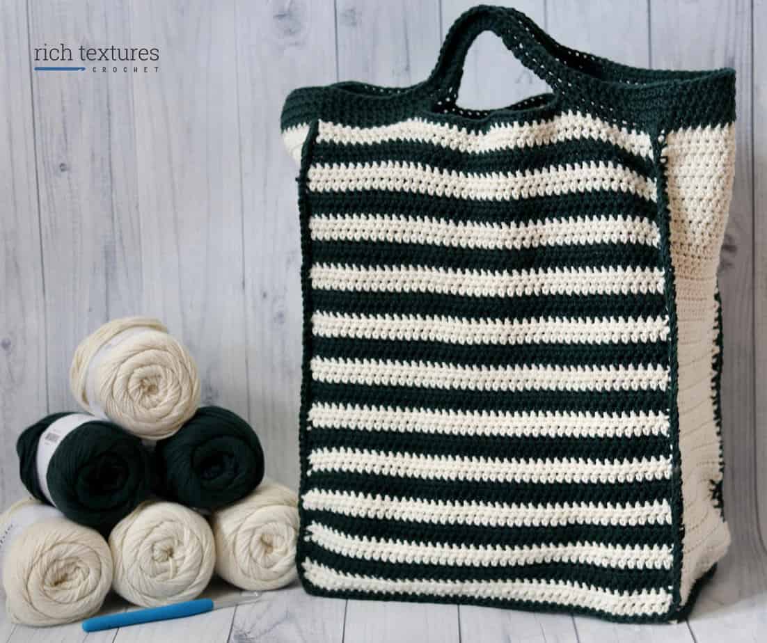 Black and white striped bag with skeins of yarn next to it.