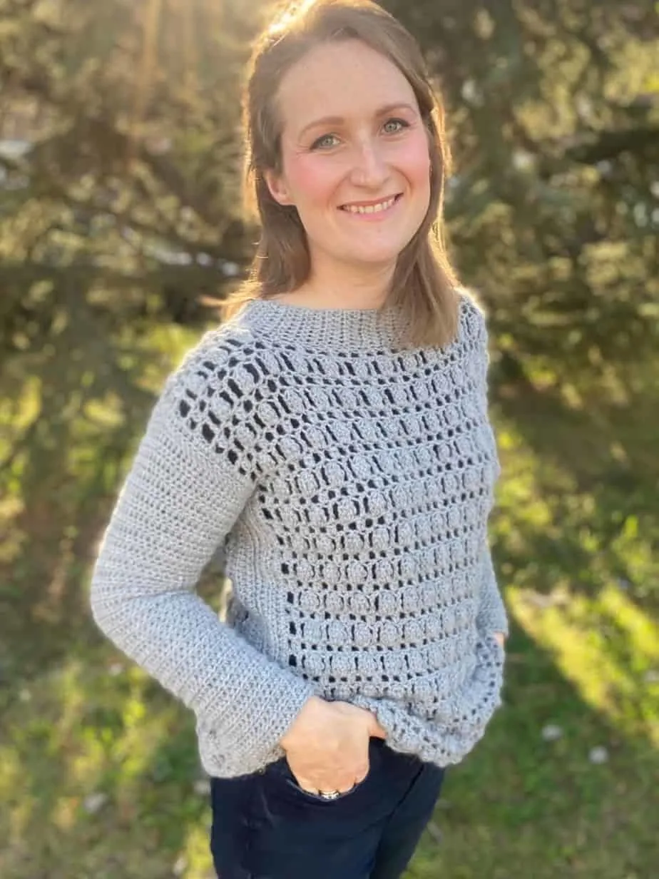 Woman wearing gray crochet sweater.