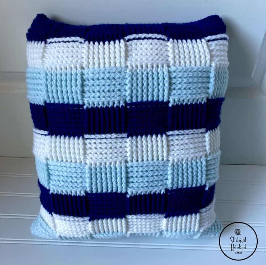 Crochet pillow cover in white, light blue and dark blue woven pattern.
