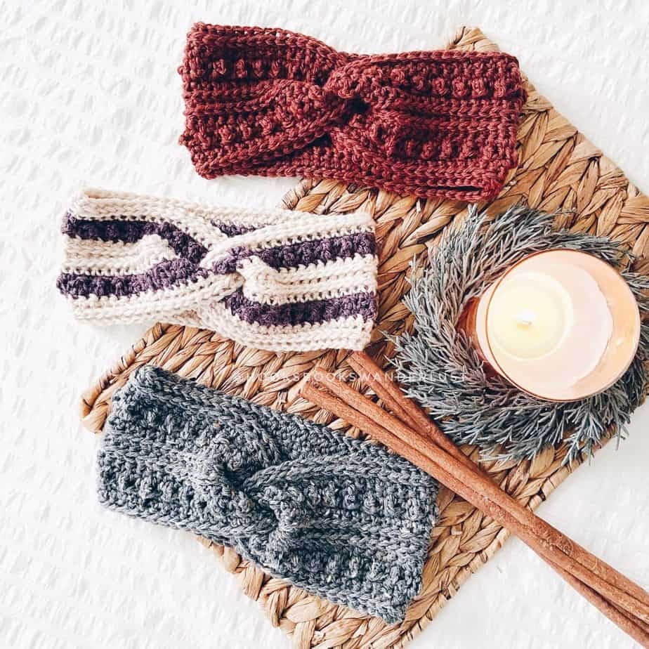 Crocheted ear warmers in three colors next to a candle.