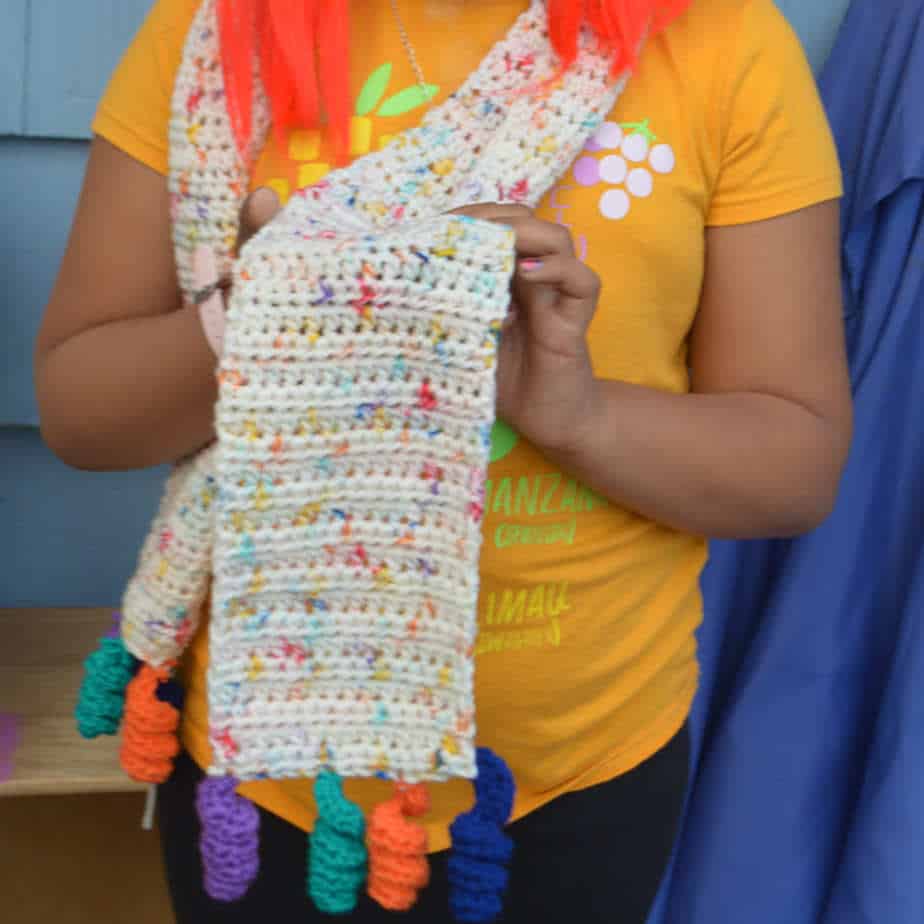 Woman wearing multi-color unicorn scarf.