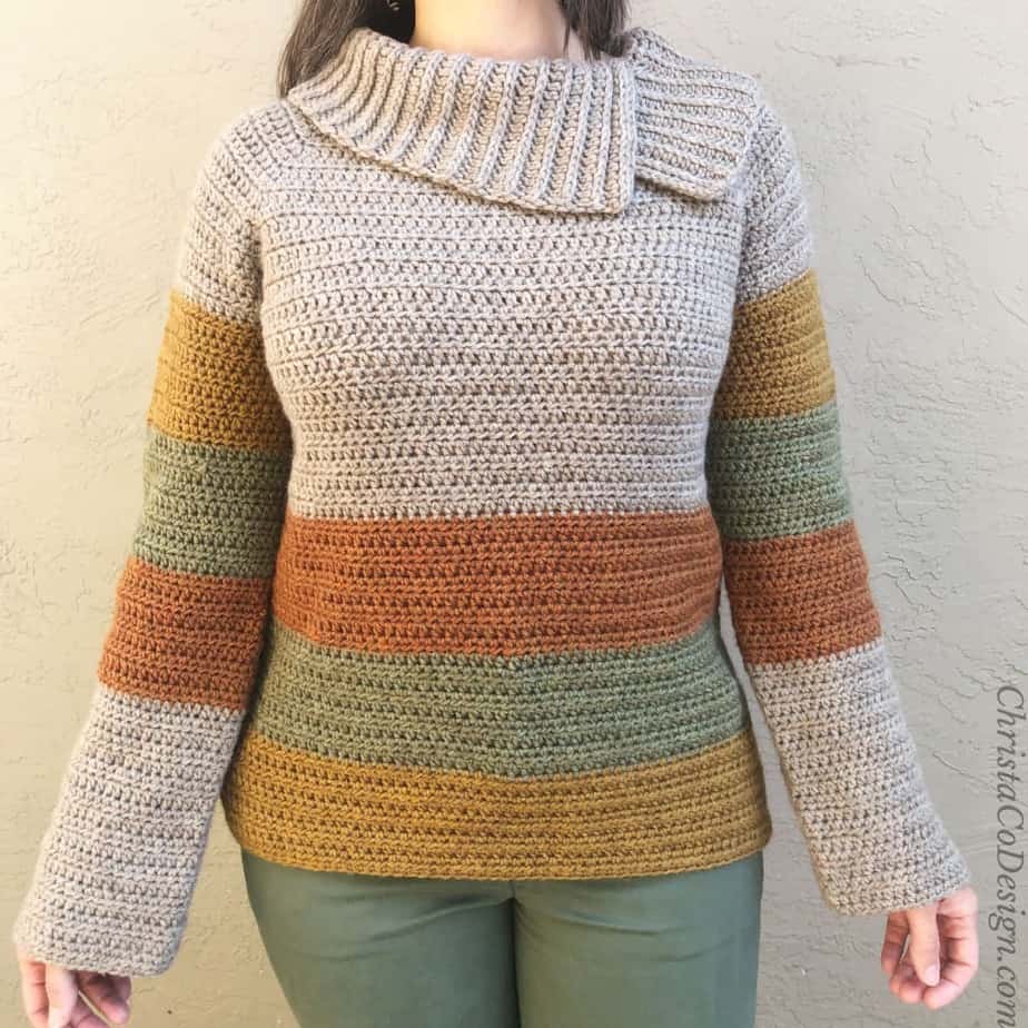 Woman's upper body wearing striped crochet sweater.