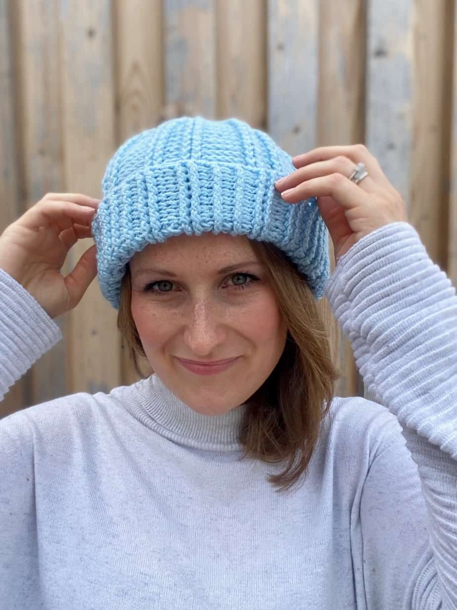 woman putting on cosy winter crochet bobble hat