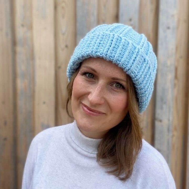 blue textured crochet bobble hat worn by a woman