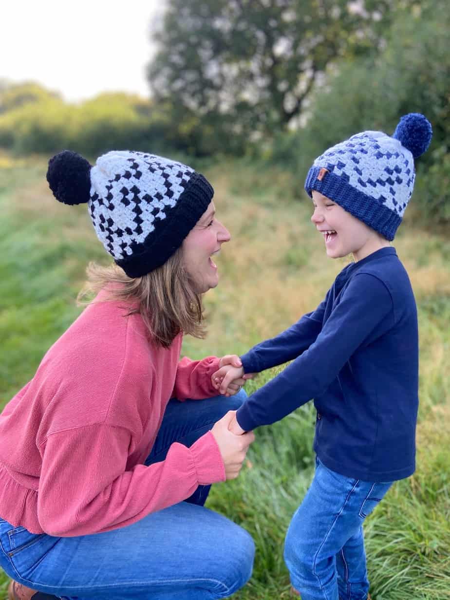 woman and child laughing together wearing c2c crochet hats in black, white and blue.