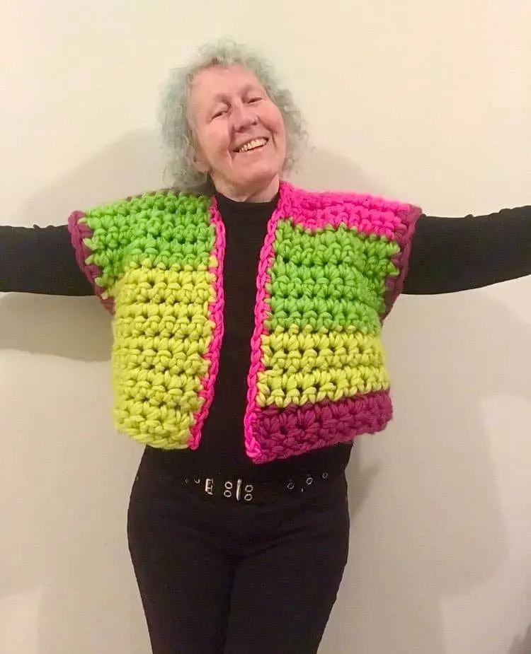 Woman with arms out to show colorful, chunky vest.
