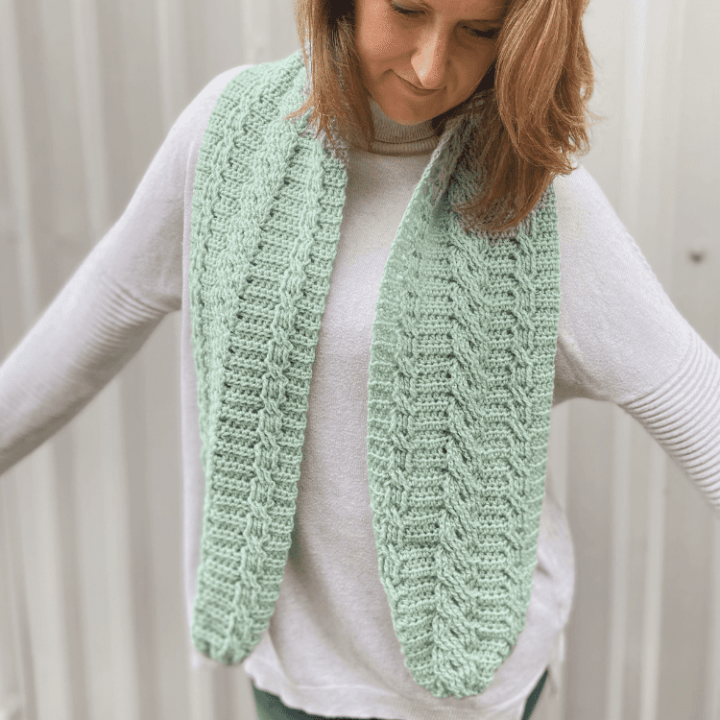 free cable crochet scarf pattern worn loosely around woman's neck