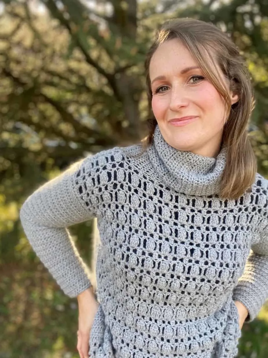 woman with hands on hips wearing grey crochet textured jumper