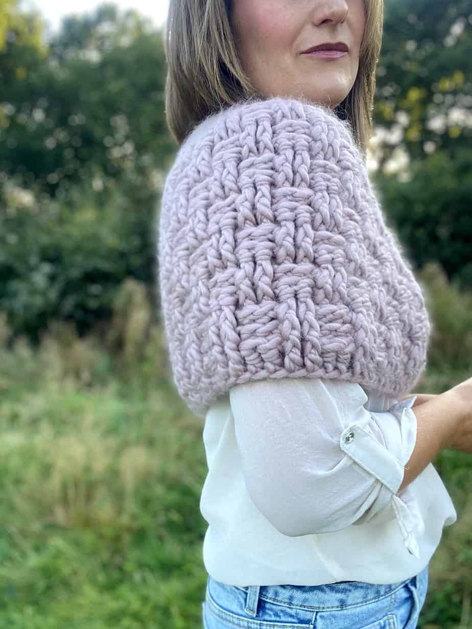 side view of woman wearing pink crochet capelet pattern in chunky yarn