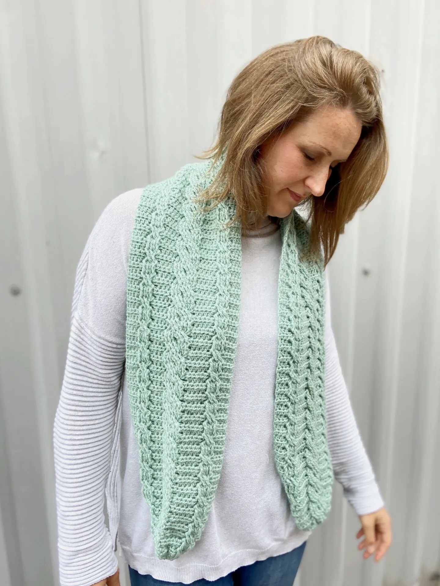 woman wearing mint green cable crochet scarf