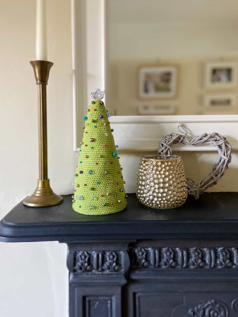 Beaded Amigurumi Crochet Christmas Tree sitting on mantle piece with mirror behind and candle sticks