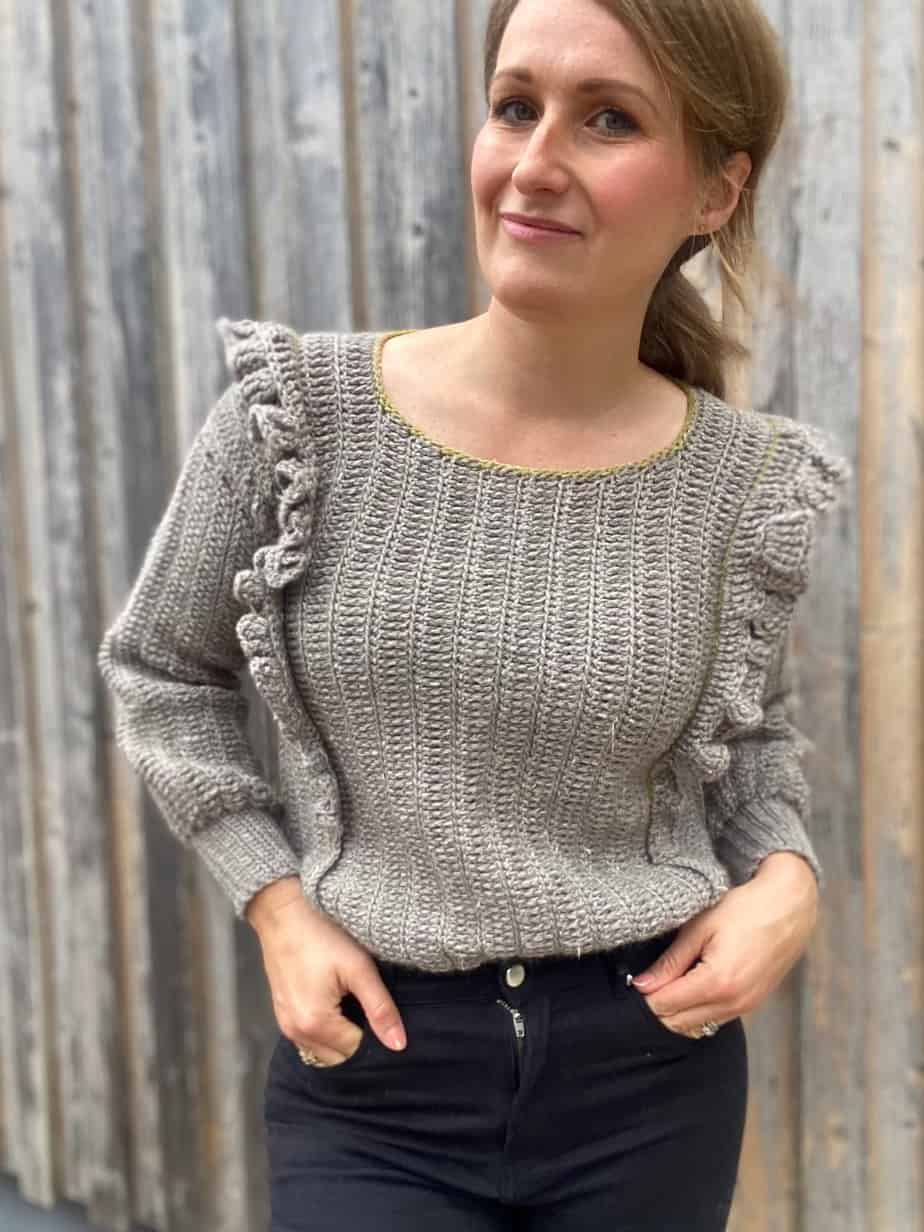 woman wearing grey ruffle stitch easy crochet sweater pattern tucked into black jeans