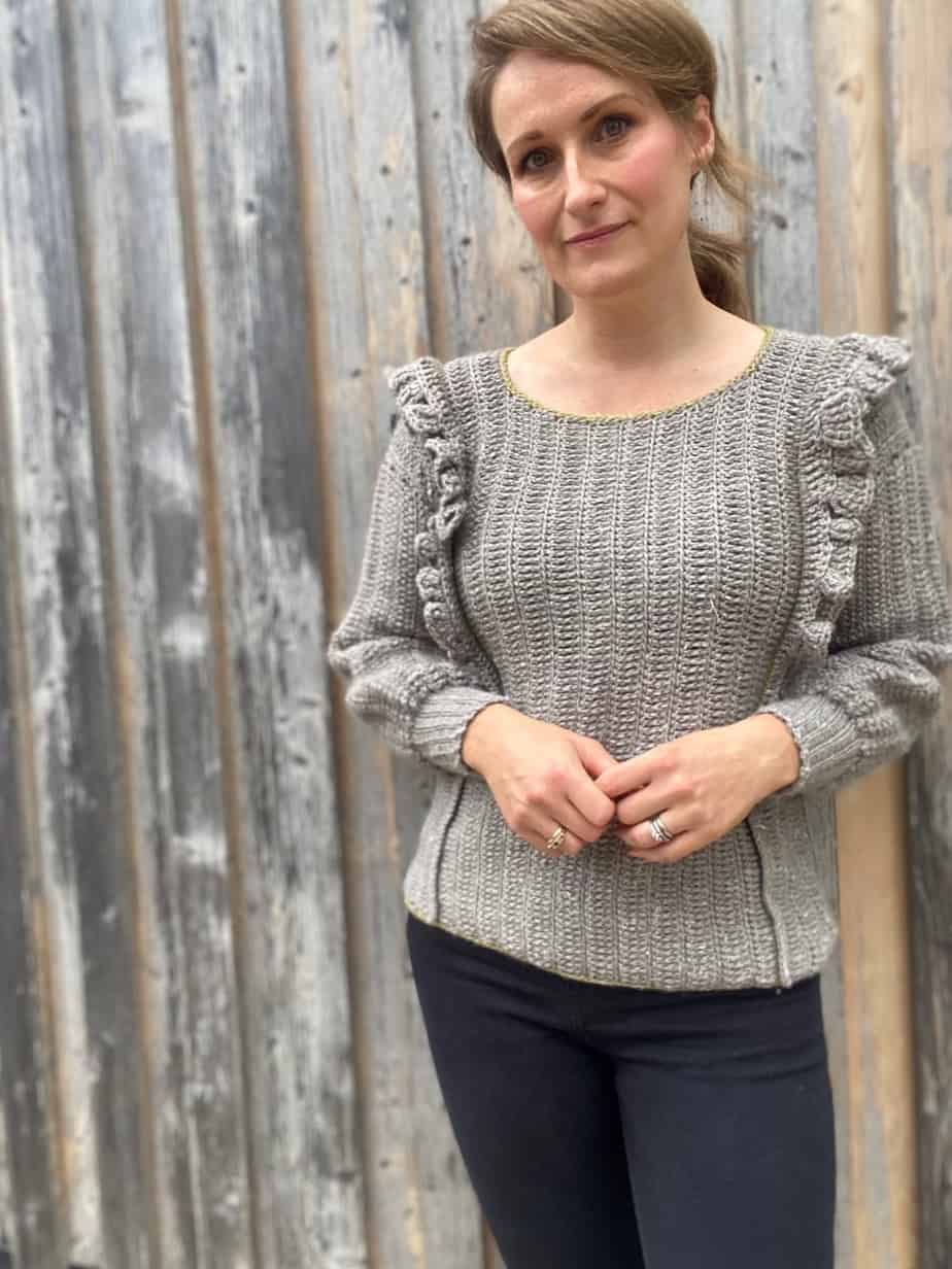 woman wearing grey modern crochet sweater with ruffle detail