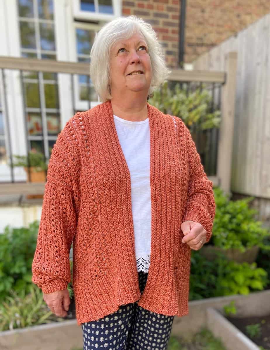 Woman wearing orange oversized crochet cardigan featuring puff stitches.