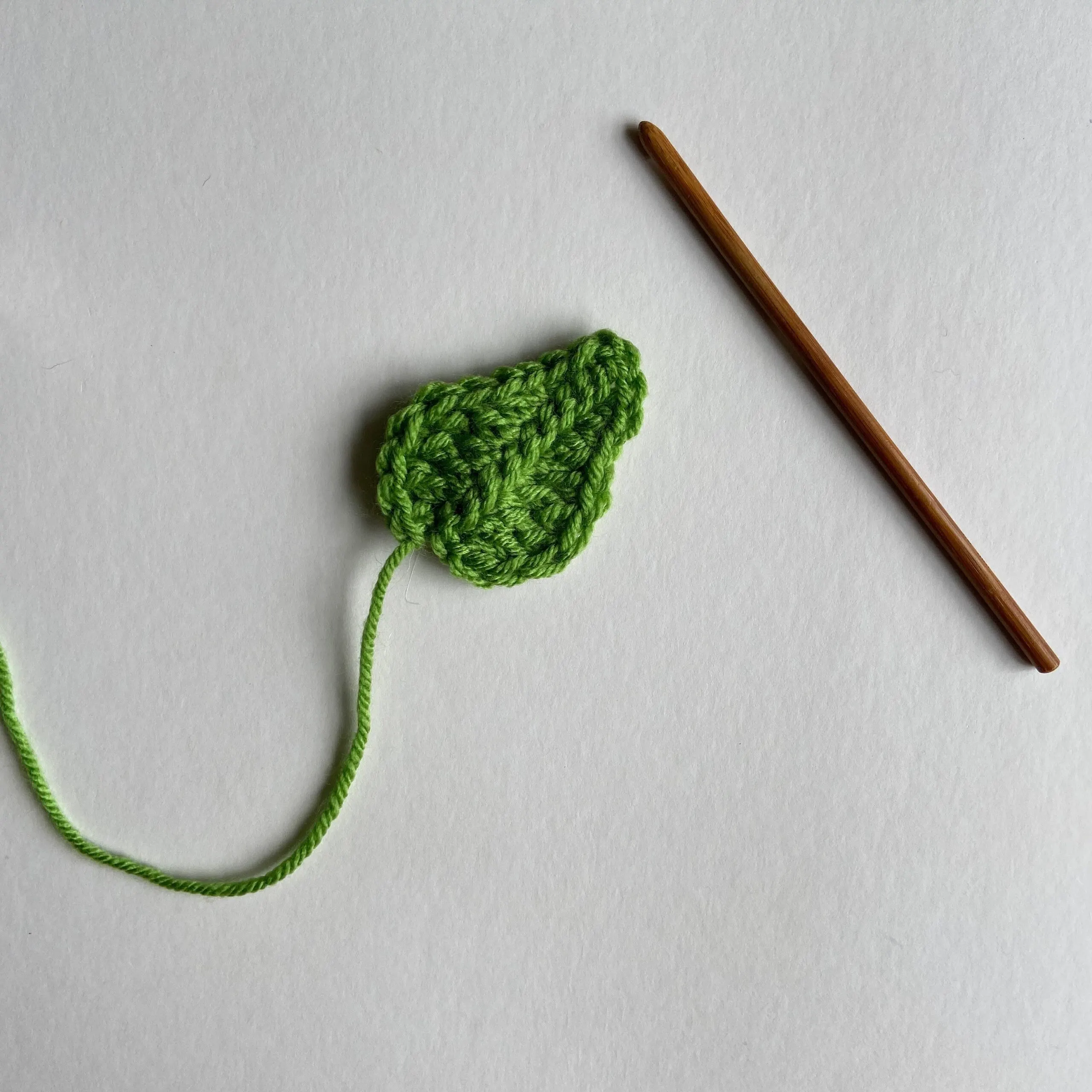 small green crochet leaf and wooden crochet hook