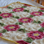 image of flower crochet blanket pattern laying on a bed with white sheets