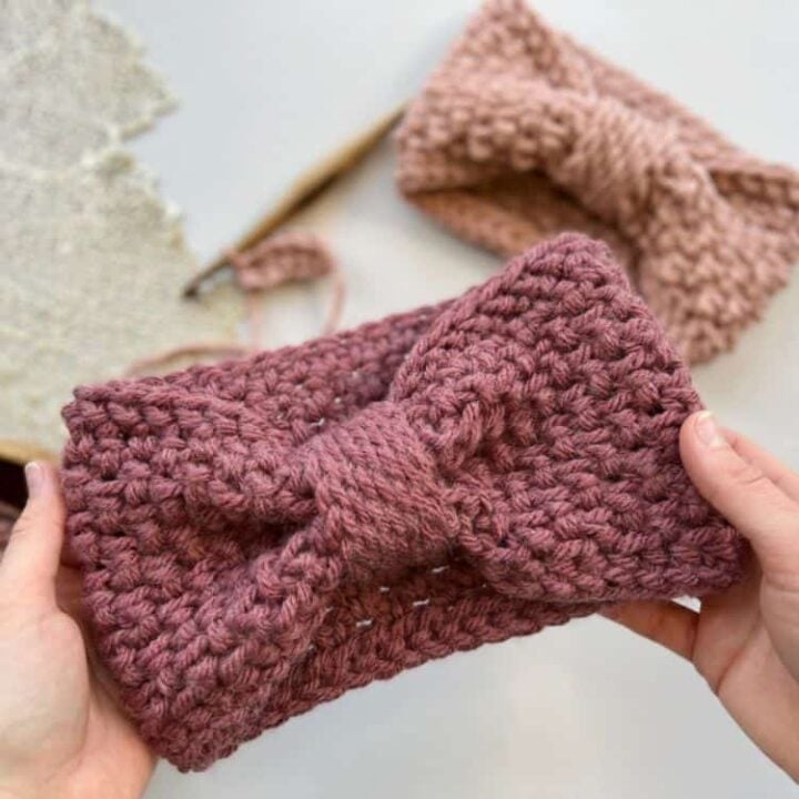 chunky crochet headband pattern being held up with crochet hook and another headband in the background