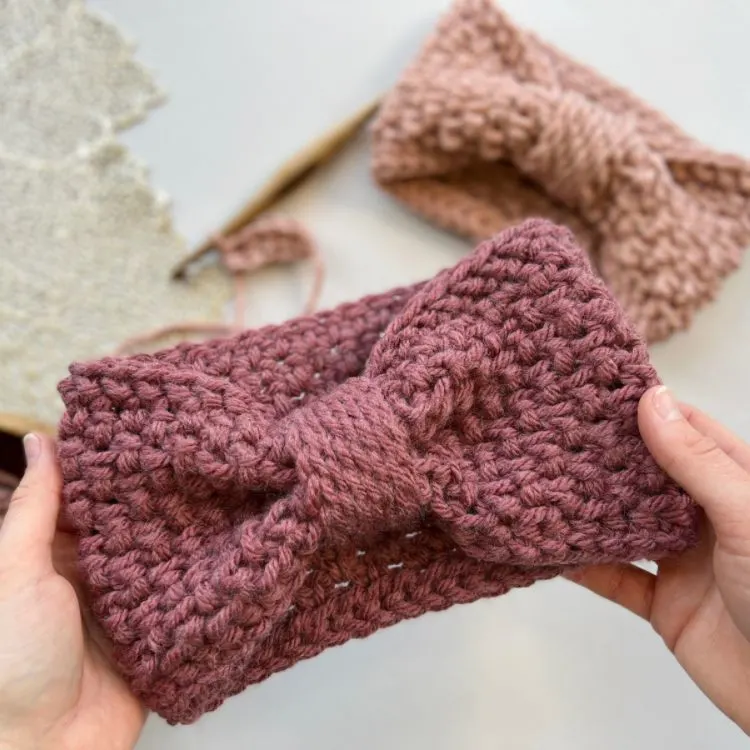 chunky crochet headband pattern being held up with crochet hook and another headband in the background