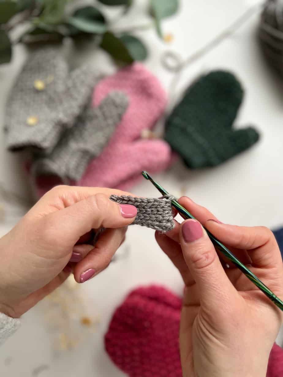 close up of rib stitch for crochet mittens with completed mittens out of focus in background