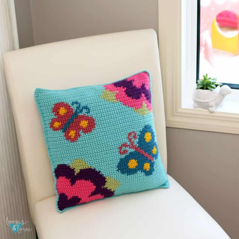 Crochet butterfly pillow on a chair.