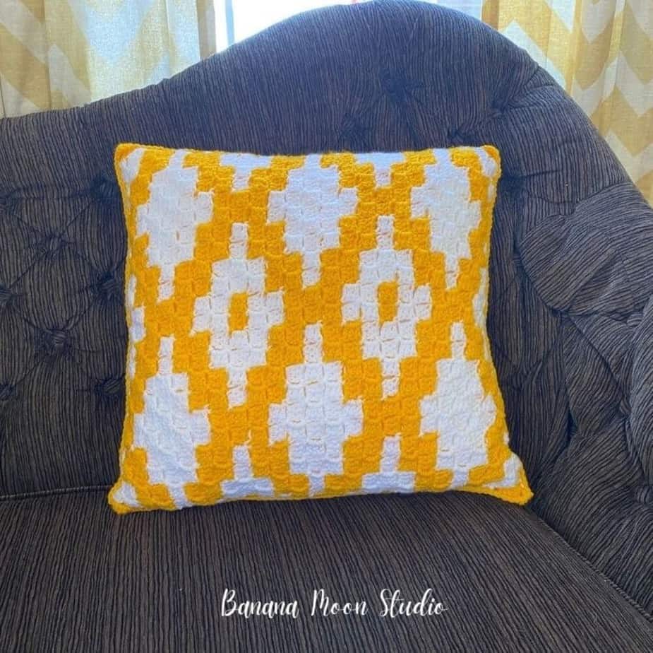 Yellow and white patterned pillow on a couch.