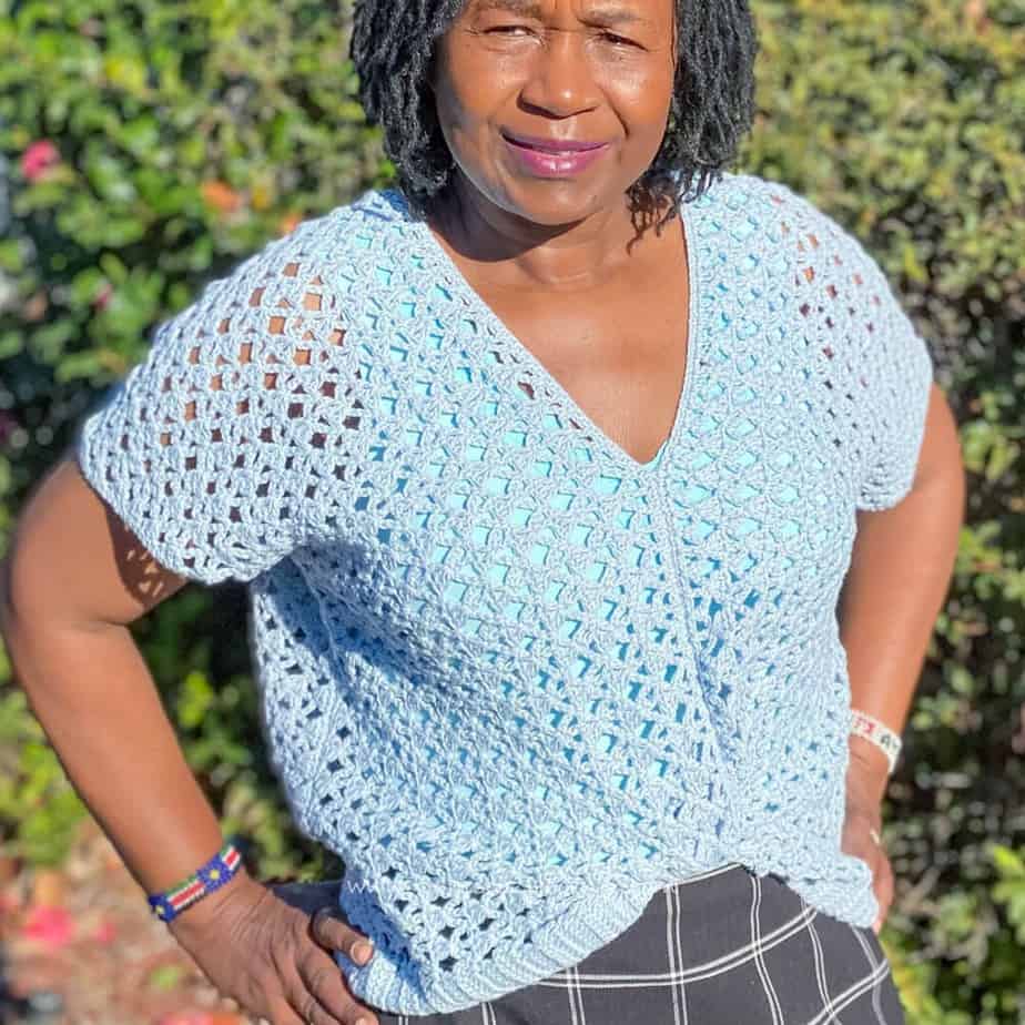 Woman wearing light blue, lacy crochet top.