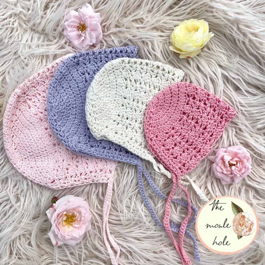 Four pastel-colored bonnets of different sizes laying on a fur rug.