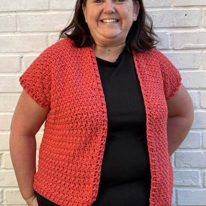 Woman wearing orange crocheted cardigan.