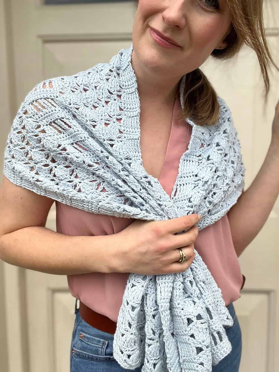 woman wearing blue lacy crochet wrap gathered with hands in the middle